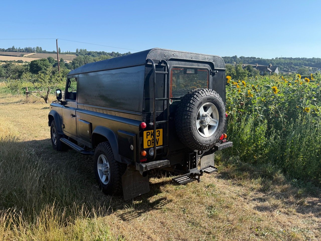 Rear three-quarter view showing the ladder, spare wheel, steps and tow ball